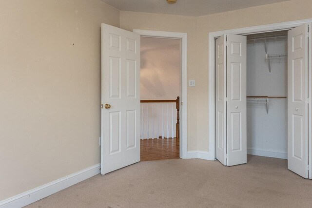 unfurnished bedroom featuring light carpet and a closet