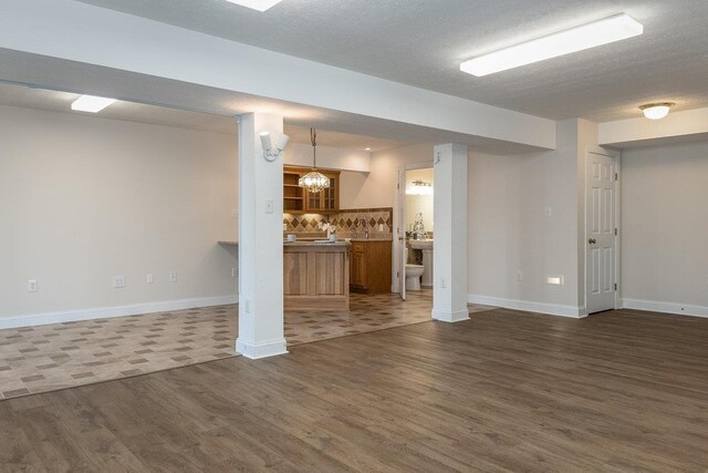 basement with dark hardwood / wood-style floors, a chandelier, and a textured ceiling