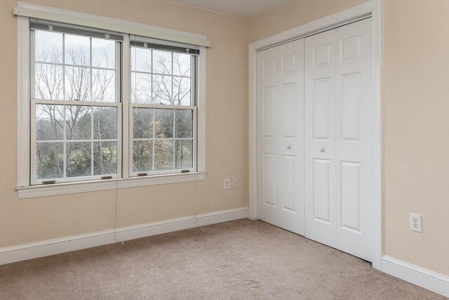 unfurnished bedroom with light carpet and a closet