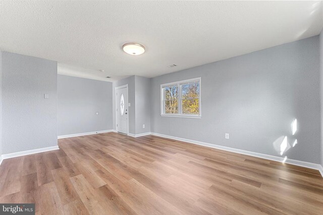 unfurnished room with light hardwood / wood-style floors and a textured ceiling