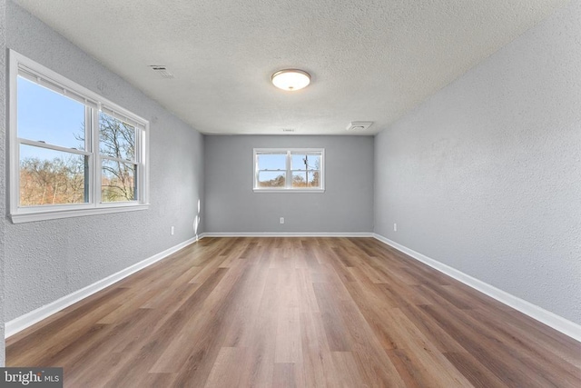 empty room with hardwood / wood-style floors and a textured ceiling