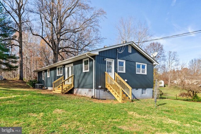 back of property featuring central AC and a lawn