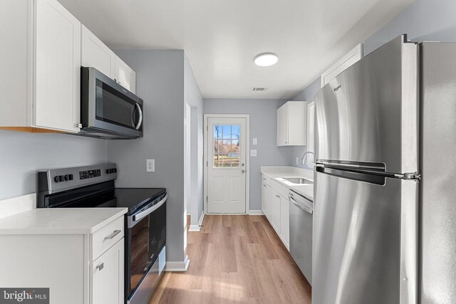 kitchen featuring white cabinetry, appliances with stainless steel finishes, sink, and light hardwood / wood-style flooring