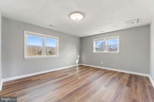 empty room with a textured ceiling and light hardwood / wood-style floors