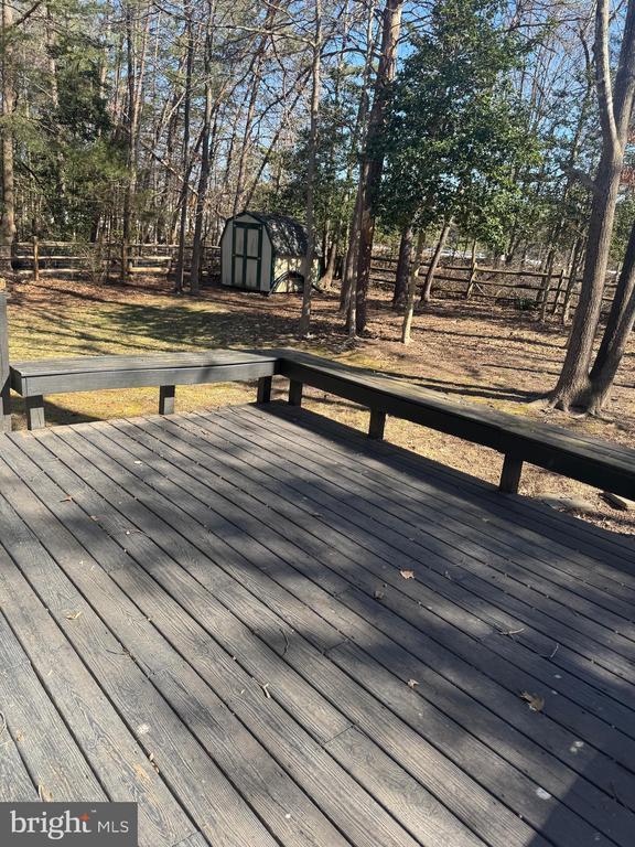 wooden terrace with fence, a storage unit, and an outdoor structure