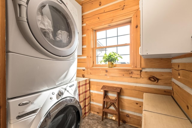 laundry area with wood walls and stacked washing maching and dryer