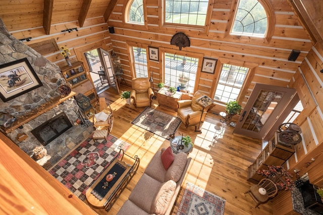 living room featuring a fireplace, high vaulted ceiling, wooden walls, and beamed ceiling