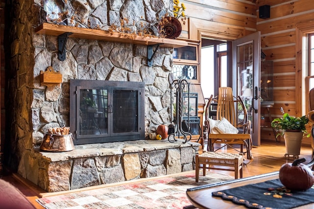 interior details with hardwood / wood-style floors, a stone fireplace, and wood walls