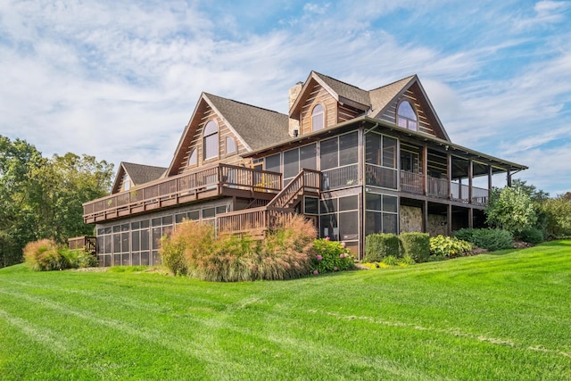 rear view of house with a wooden deck, a lawn, and a sunroom