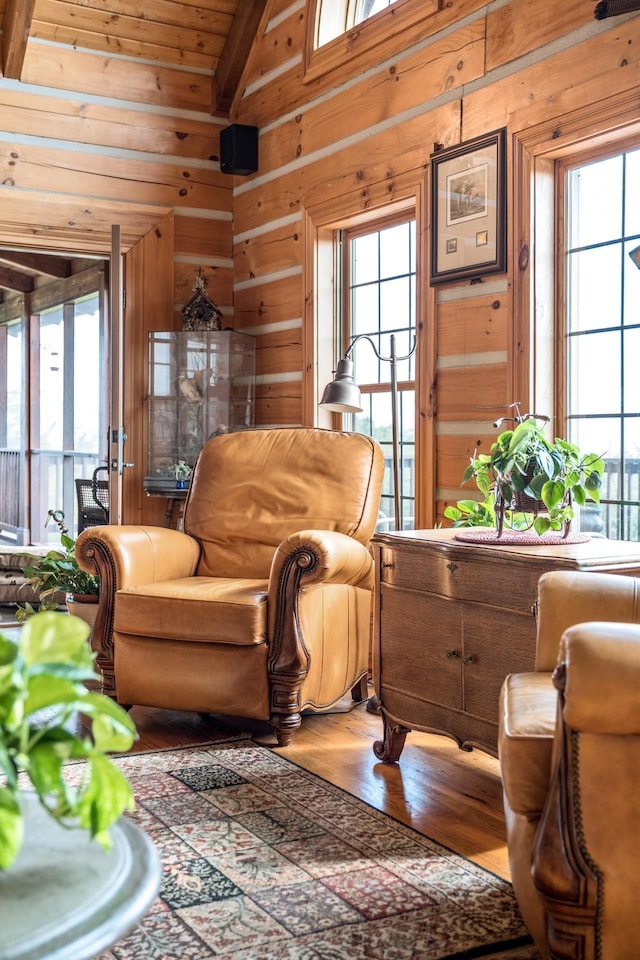 living area featuring hardwood / wood-style flooring, a healthy amount of sunlight, and wooden walls