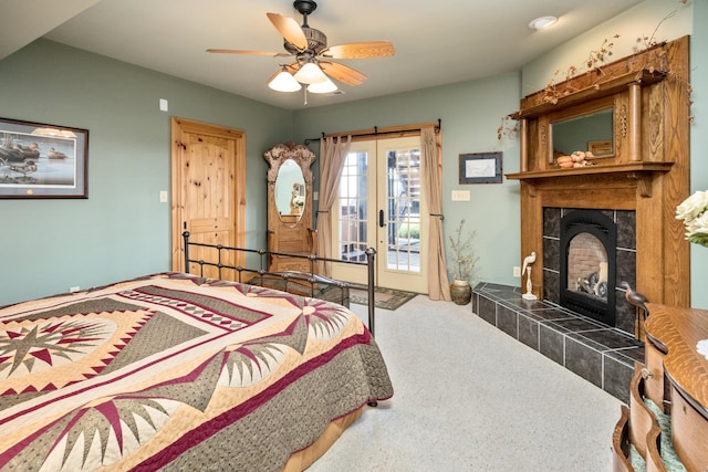 bedroom featuring a tile fireplace, carpet, access to outside, ceiling fan, and french doors