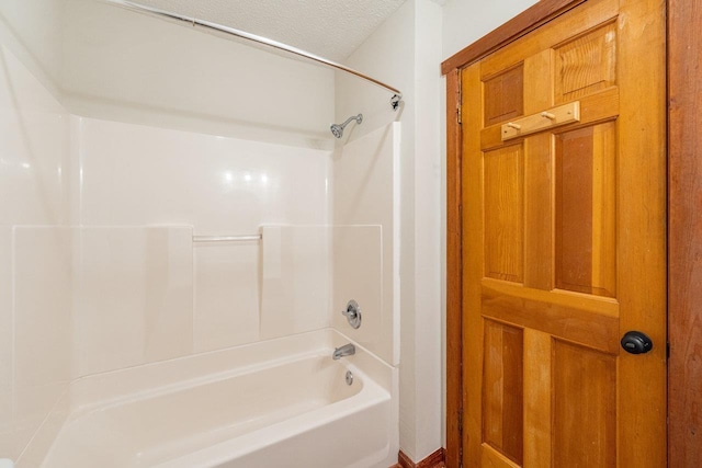 bathroom with a textured ceiling and shower / bathing tub combination