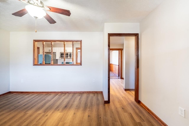 empty room featuring a textured ceiling, baseboards, and wood finished floors