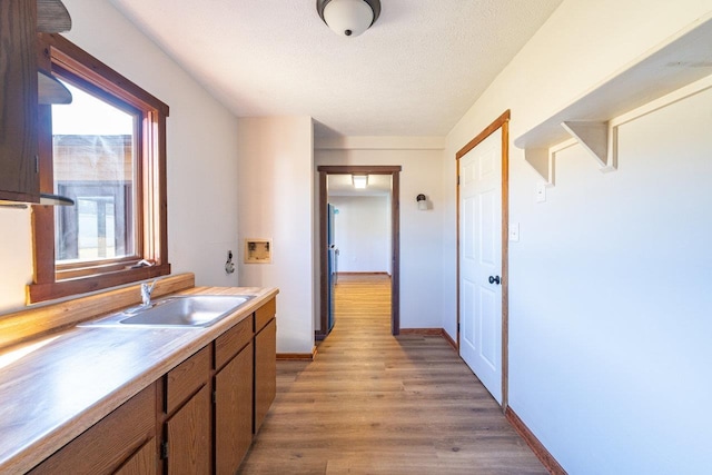 interior space featuring a sink, a textured ceiling, baseboards, and wood finished floors