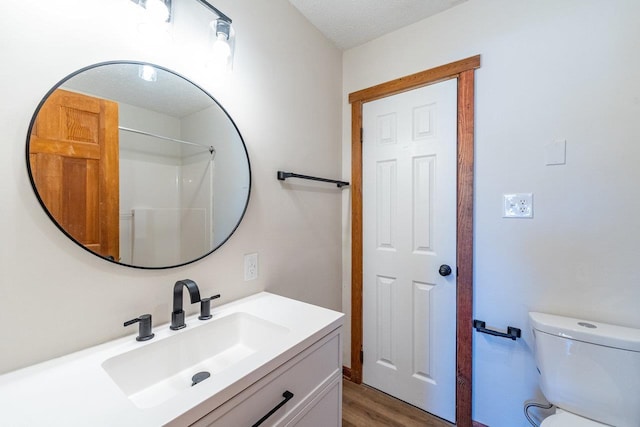 bathroom featuring toilet, wood finished floors, and vanity