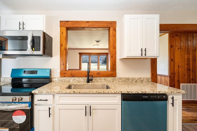 kitchen with appliances with stainless steel finishes, a sink, visible vents, and light stone countertops