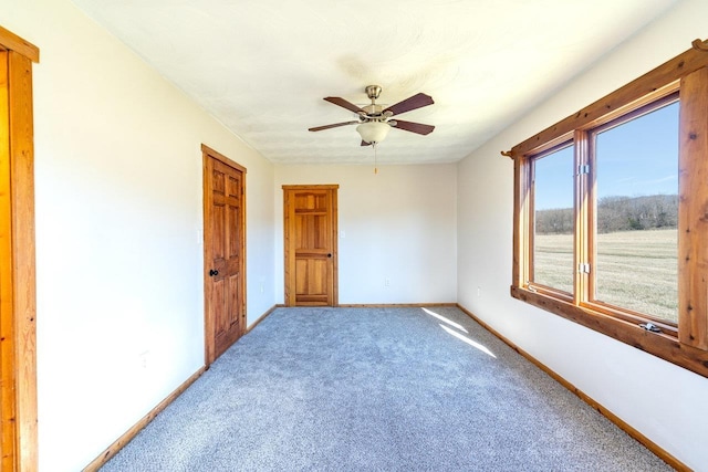 spare room with carpet, ceiling fan, and baseboards