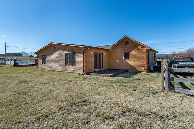 back of property featuring log exterior, a yard, and fence