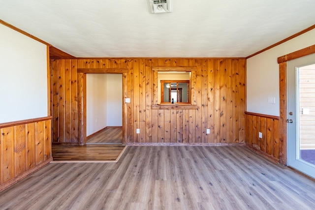 empty room with a wealth of natural light, wainscoting, and wood finished floors