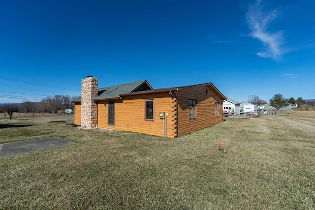 view of home's exterior with roof mounted solar panels, a chimney, and a yard