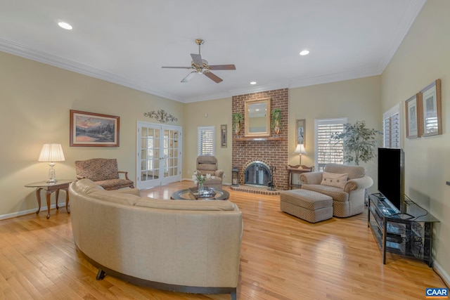 living room featuring light wood finished floors, a brick fireplace, crown molding, and french doors