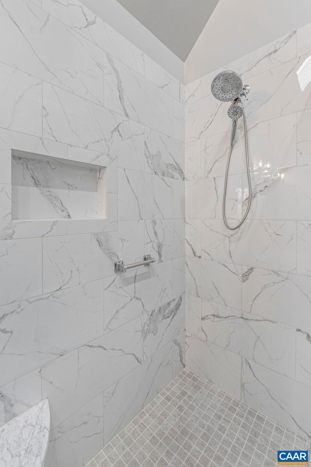 full bath with lofted ceiling and tiled shower