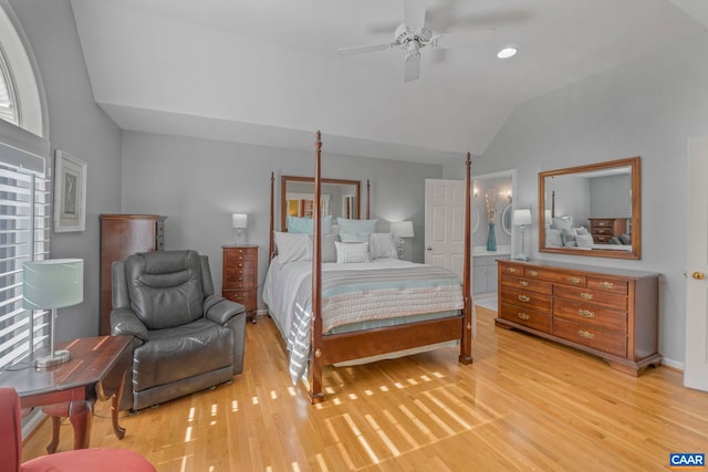 bedroom featuring light wood-type flooring, ensuite bath, vaulted ceiling, and a ceiling fan