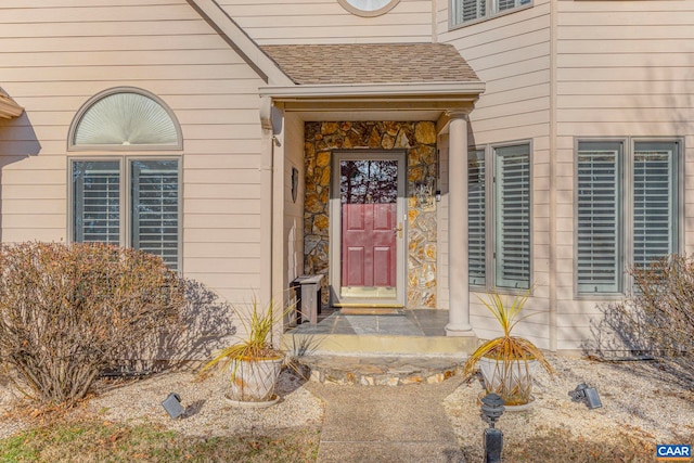 entrance to property featuring roof with shingles