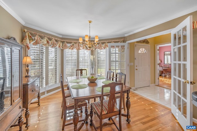 dining room with light wood-type flooring, an inviting chandelier, and crown molding