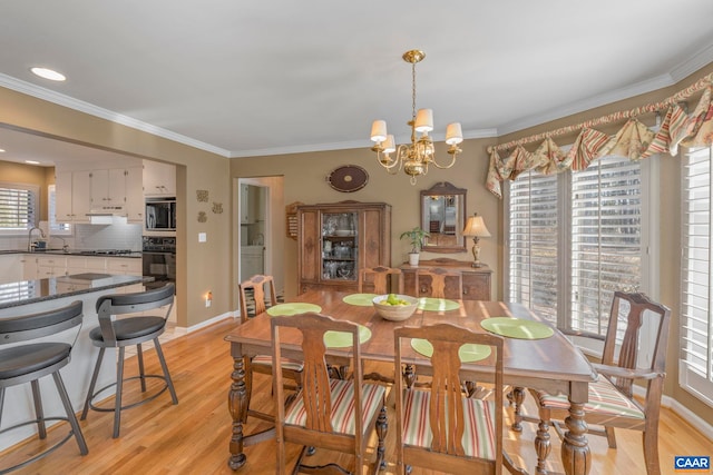 dining space featuring baseboards, light wood-style flooring, a chandelier, and crown molding