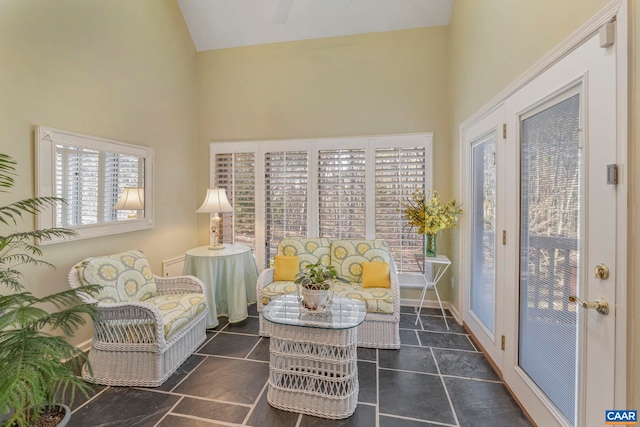 living area featuring high vaulted ceiling, tile patterned flooring, and baseboards