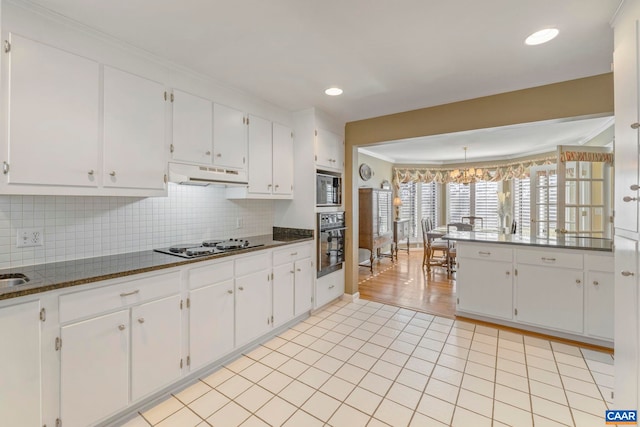 kitchen featuring tasteful backsplash, white cabinets, built in microwave, under cabinet range hood, and black oven