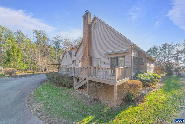 view of side of home with stairs, a chimney, and a deck