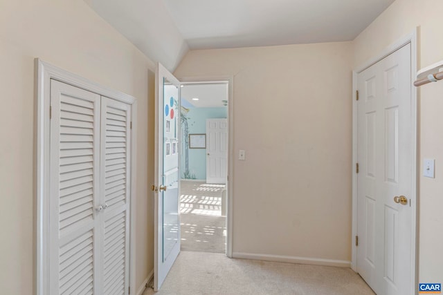 hallway with baseboards and light colored carpet