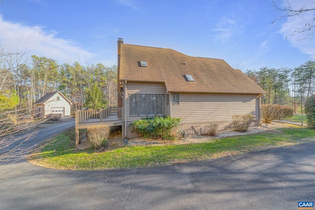 view of property exterior featuring roof with shingles, a chimney, and a wooden deck