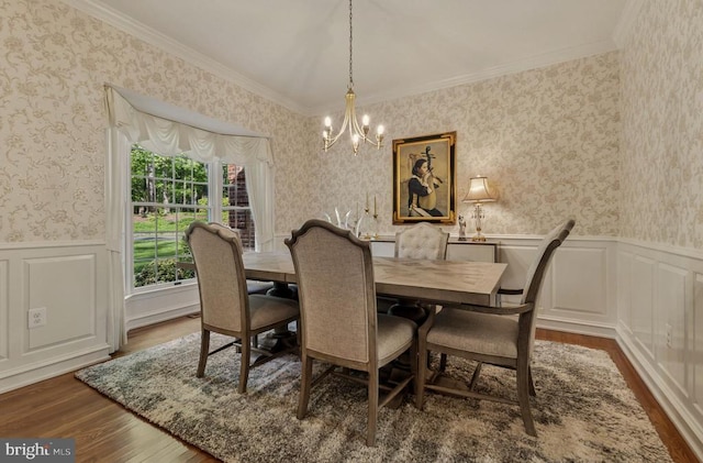 dining area featuring wainscoting, a chandelier, ornamental molding, and dark wood-type flooring