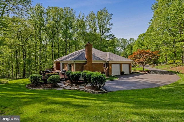 view of side of home with driveway, a chimney, a lawn, a deck, and a garage