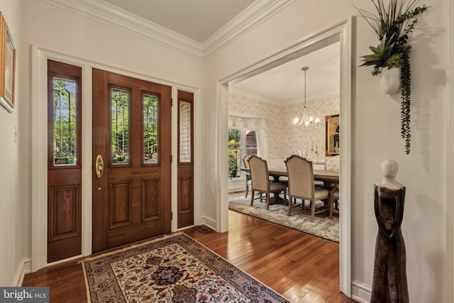 entryway featuring crown molding, baseboards, dark wood-style floors, a notable chandelier, and wallpapered walls