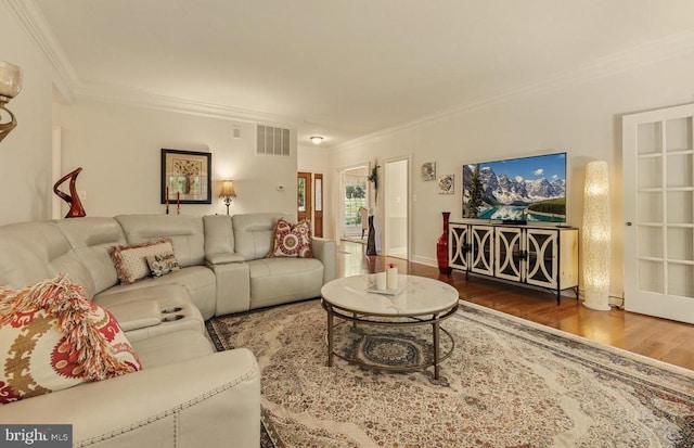 living room featuring crown molding, wood finished floors, and visible vents