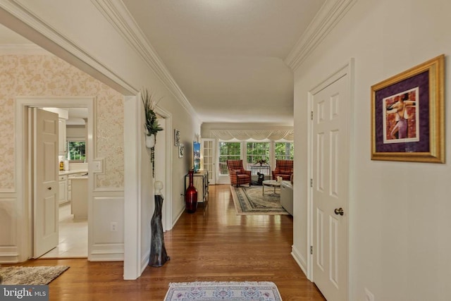 hall featuring wallpapered walls, ornamental molding, and wood finished floors