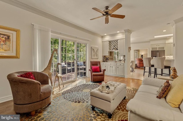 living area with ceiling fan, baseboards, light wood-style floors, ornamental molding, and recessed lighting