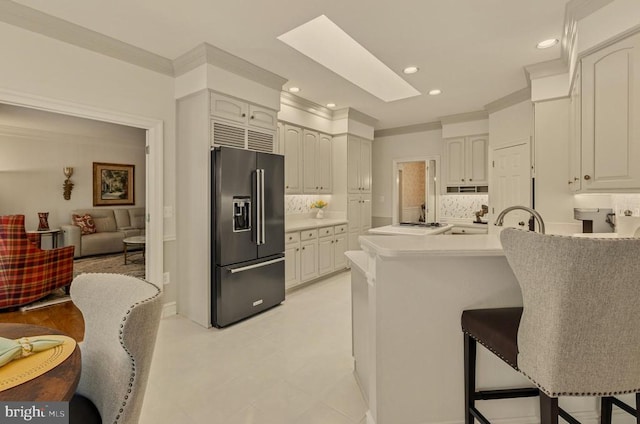 kitchen with a breakfast bar area, backsplash, a peninsula, recessed lighting, and high end fridge