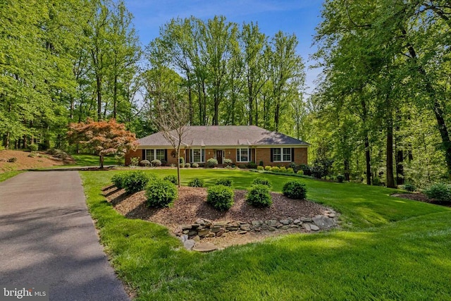 ranch-style house with a front lawn and aphalt driveway