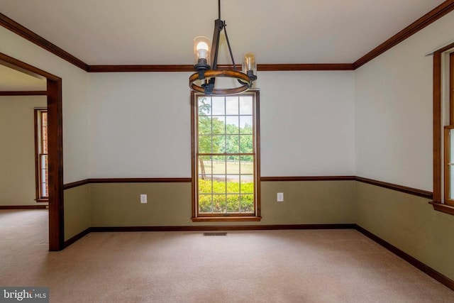 carpeted spare room with ornamental molding and a chandelier