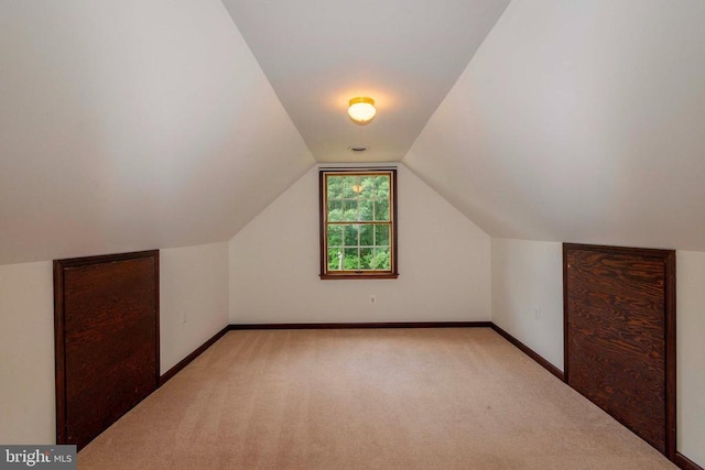 bonus room with light colored carpet and vaulted ceiling