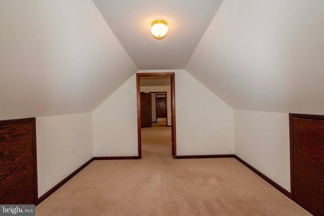 additional living space featuring light colored carpet and vaulted ceiling