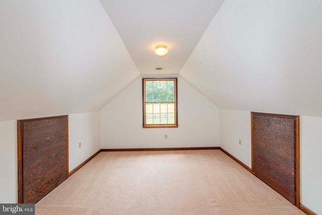 bonus room with lofted ceiling and light carpet