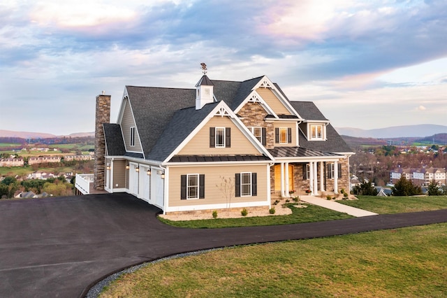 view of front of property featuring a garage, a mountain view, covered porch, and a front lawn