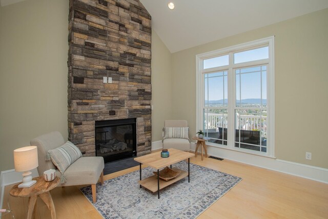 living room with high vaulted ceiling, a fireplace, and light hardwood / wood-style floors