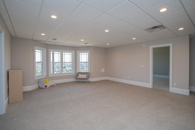 empty room featuring a drop ceiling and light colored carpet